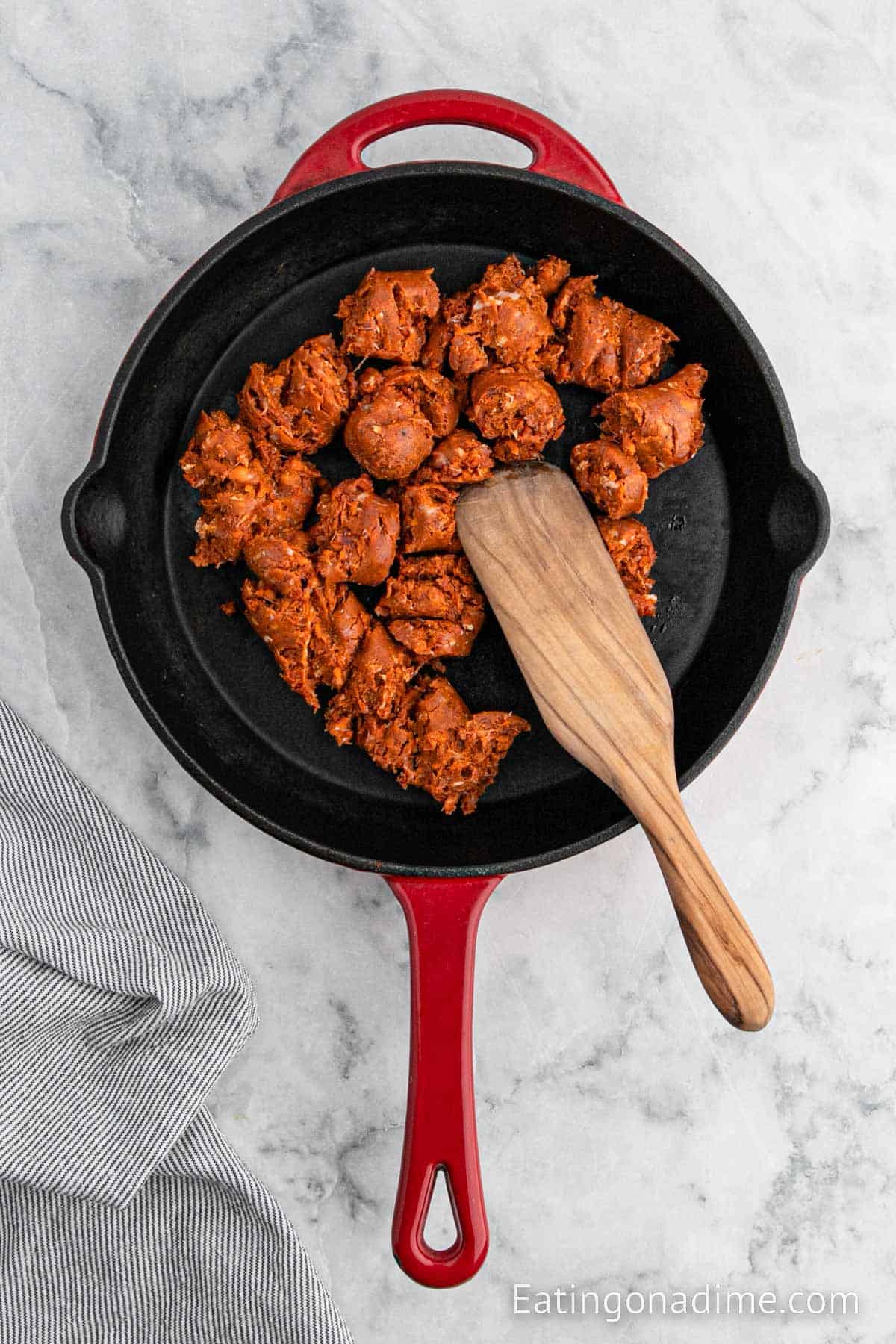 Cooking ground chorizo in a cast iron skillet with a wooden spoon