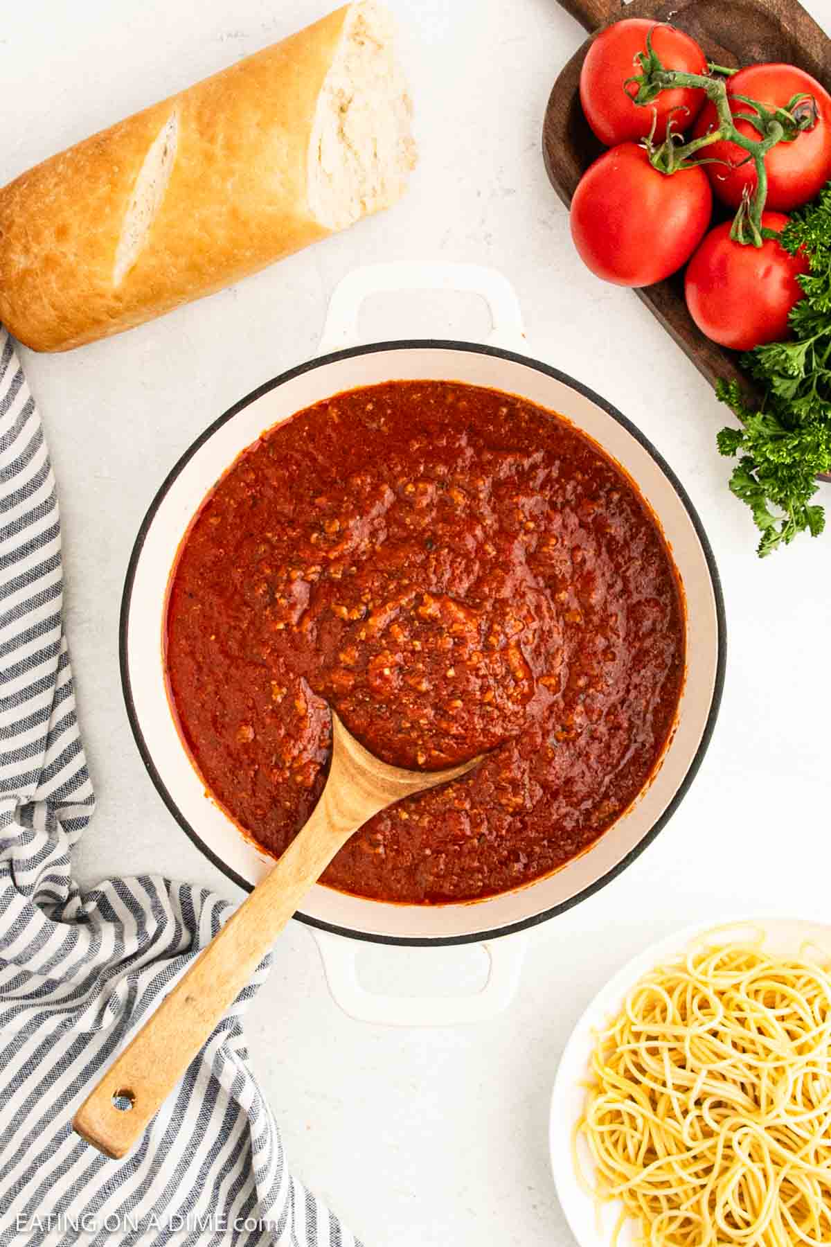 Red sauce in a large pot with a wooden spoon.