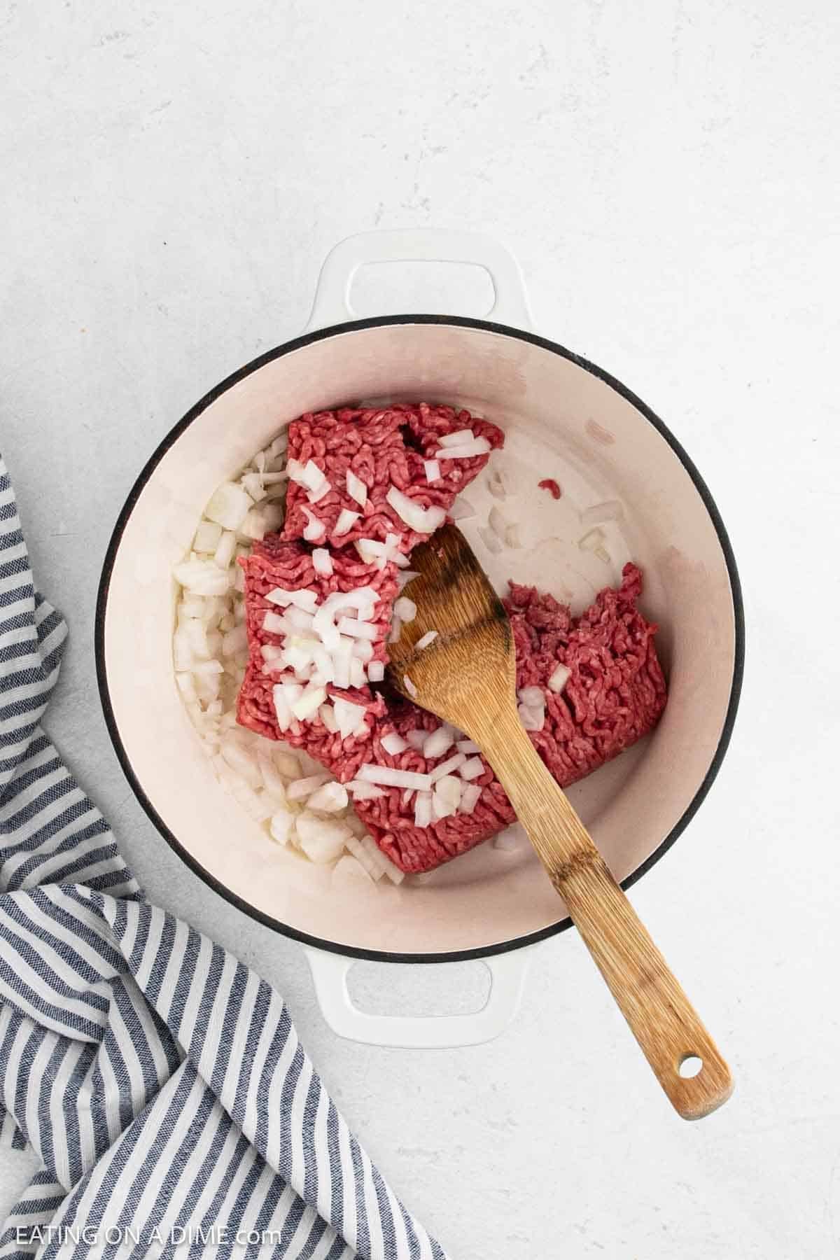 Ground beef with chopped onions in a large pot.