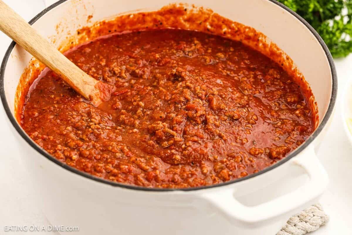 Bolognese sauce in a large pot with a wooden spoon.