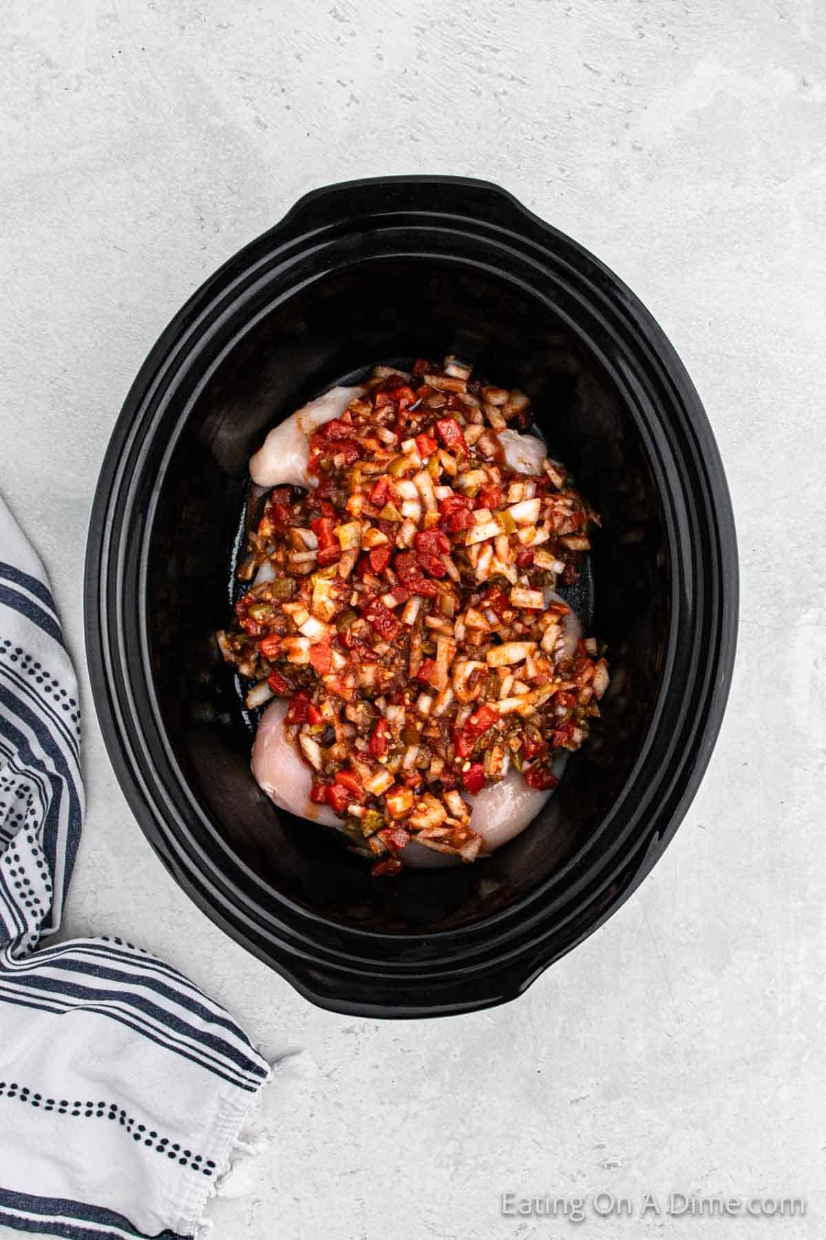 Pouring the sauce over the chicken over in the slow cooker