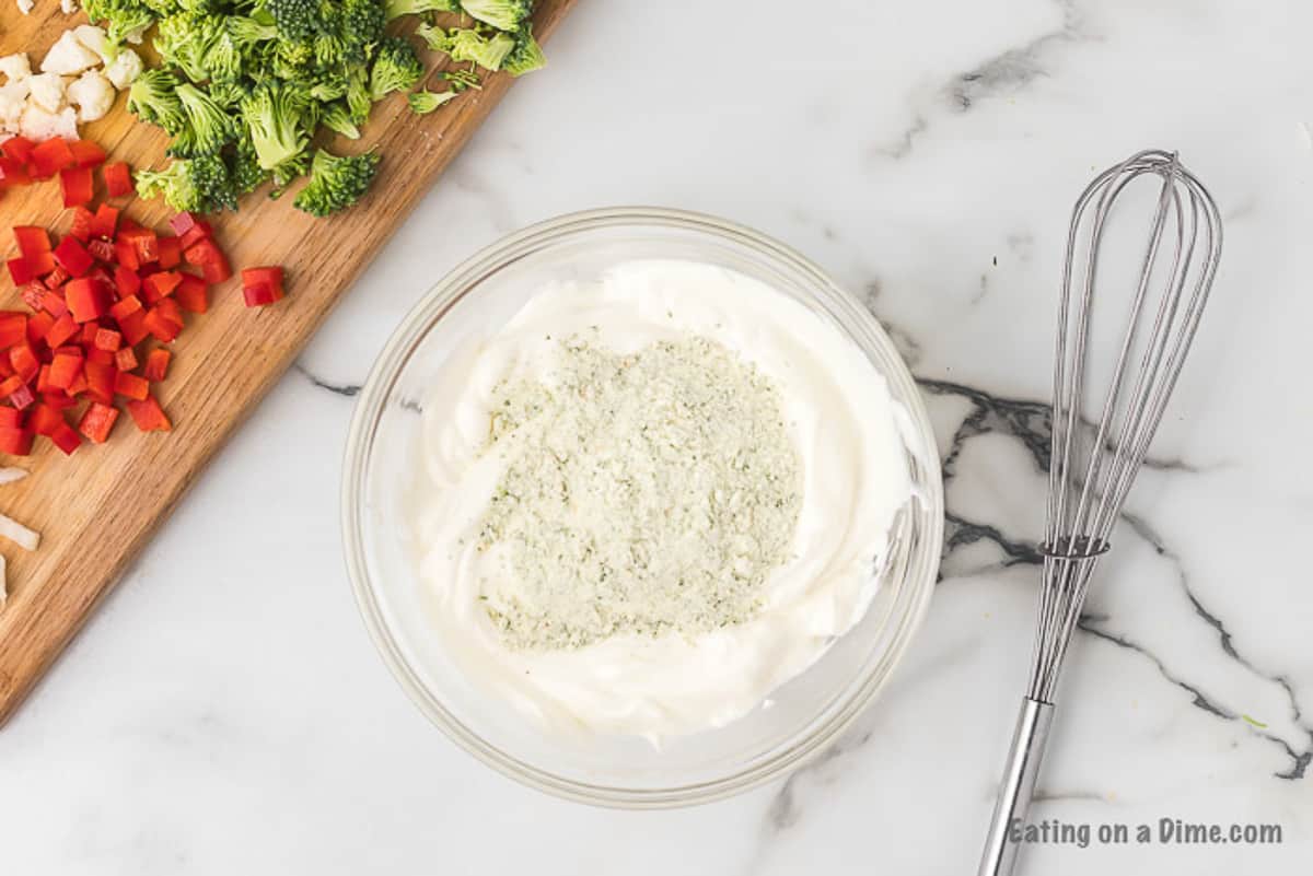 Combining the sour cream and ranch mix together in a bowl