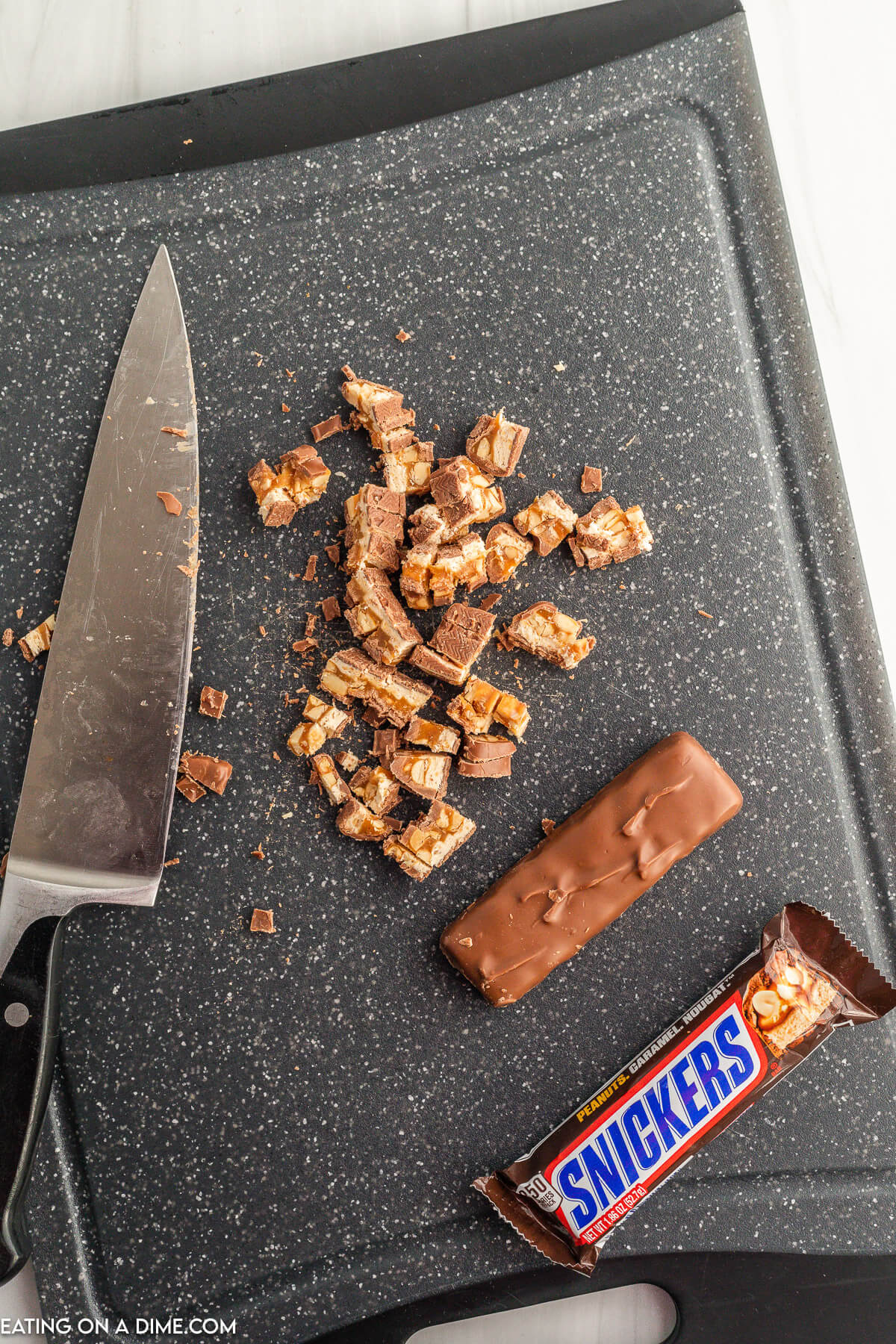 Chopped Snicker Bars on a cutting board with a knife