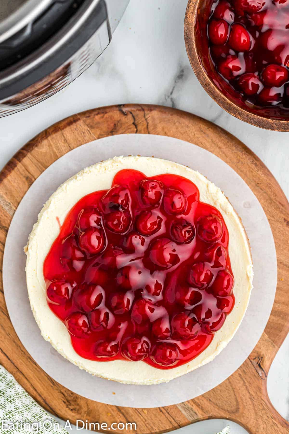 Cheesecake topped with cherries on a wooden platter