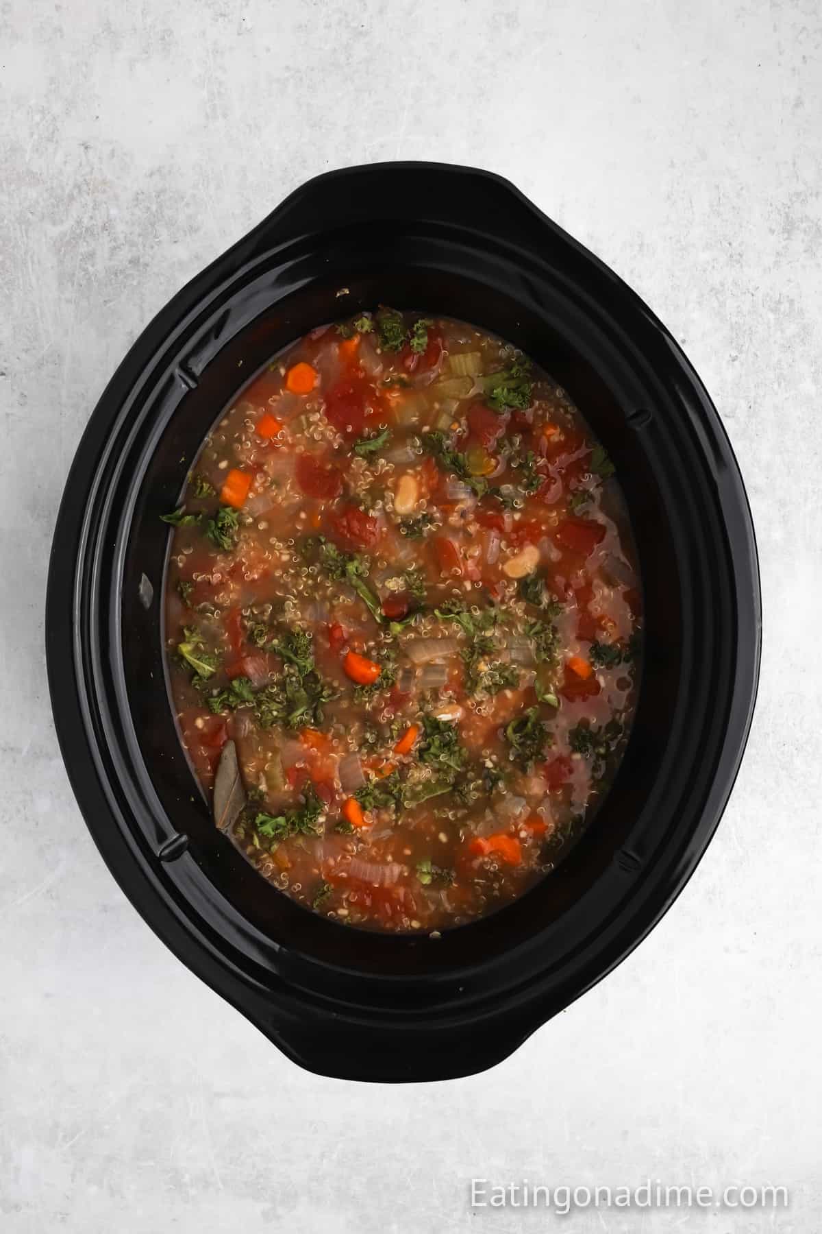 Stirring in the kale to the cooked ingredients into the slow cooker