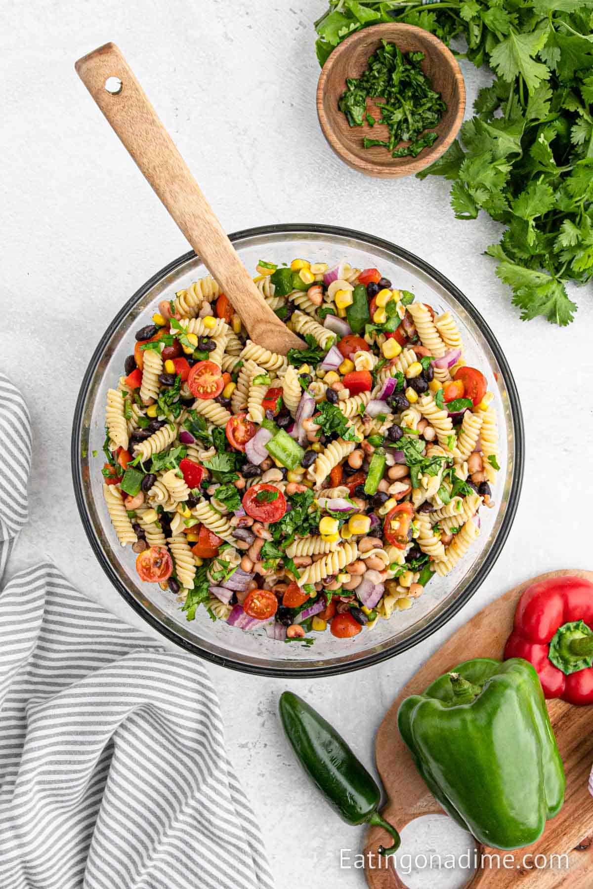 Mixing the pasta ingredients with the dressing in a bowl with a wooden spoon