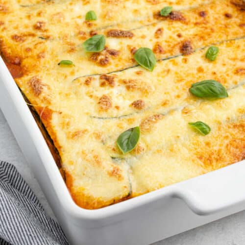 Cheesy zucchini lasagna in a white baking dish.
