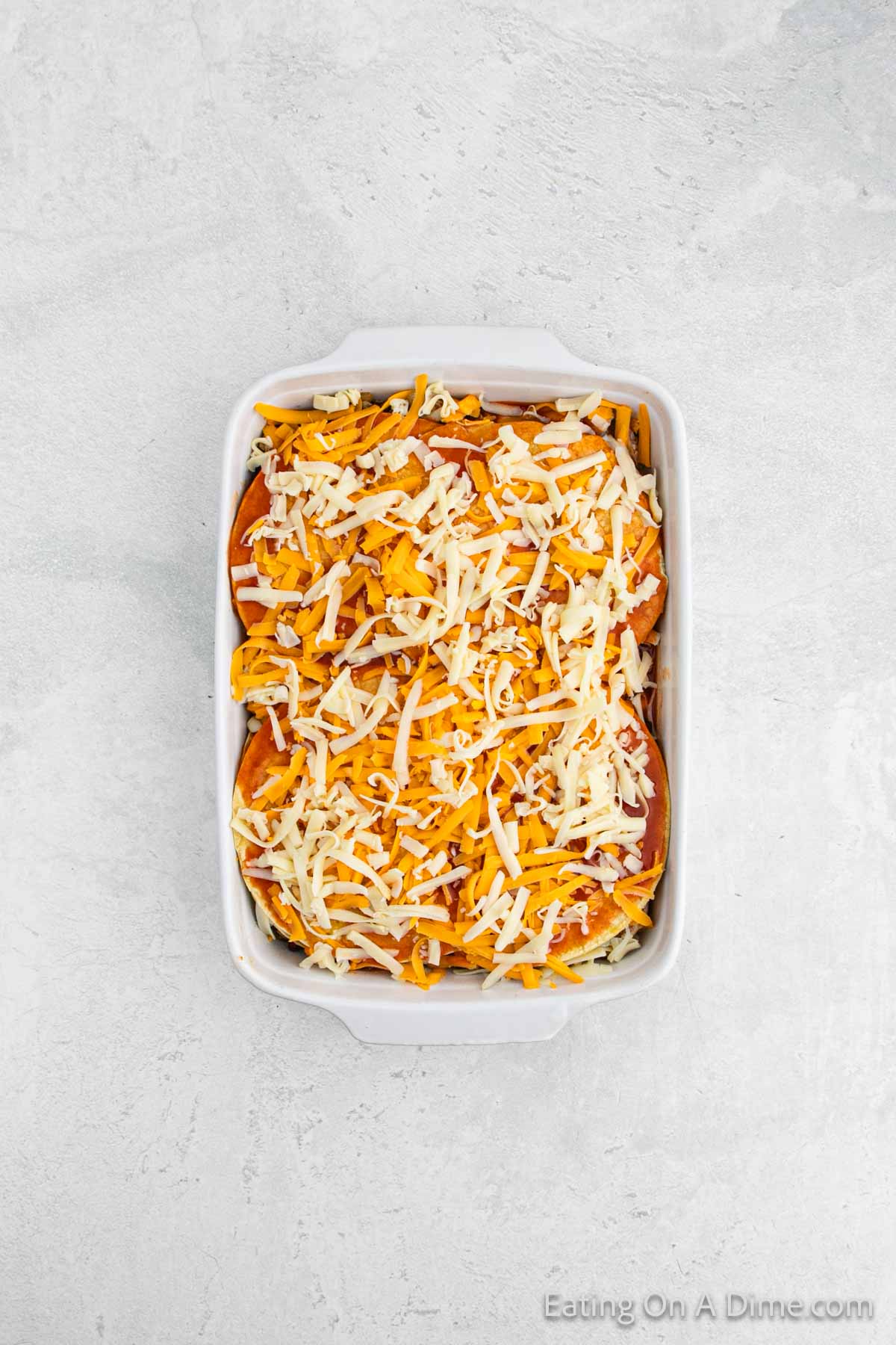 The casserole layered with more tortillas, chicken mixture, beans, shredded cheese and enchilada sauce. 