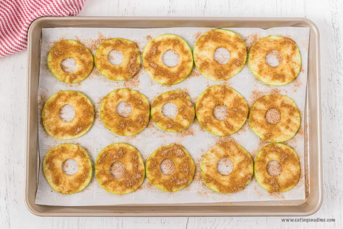 The cinnamon and sugar mixture sprinkled on top of the apple slices on the baking sheet.  
