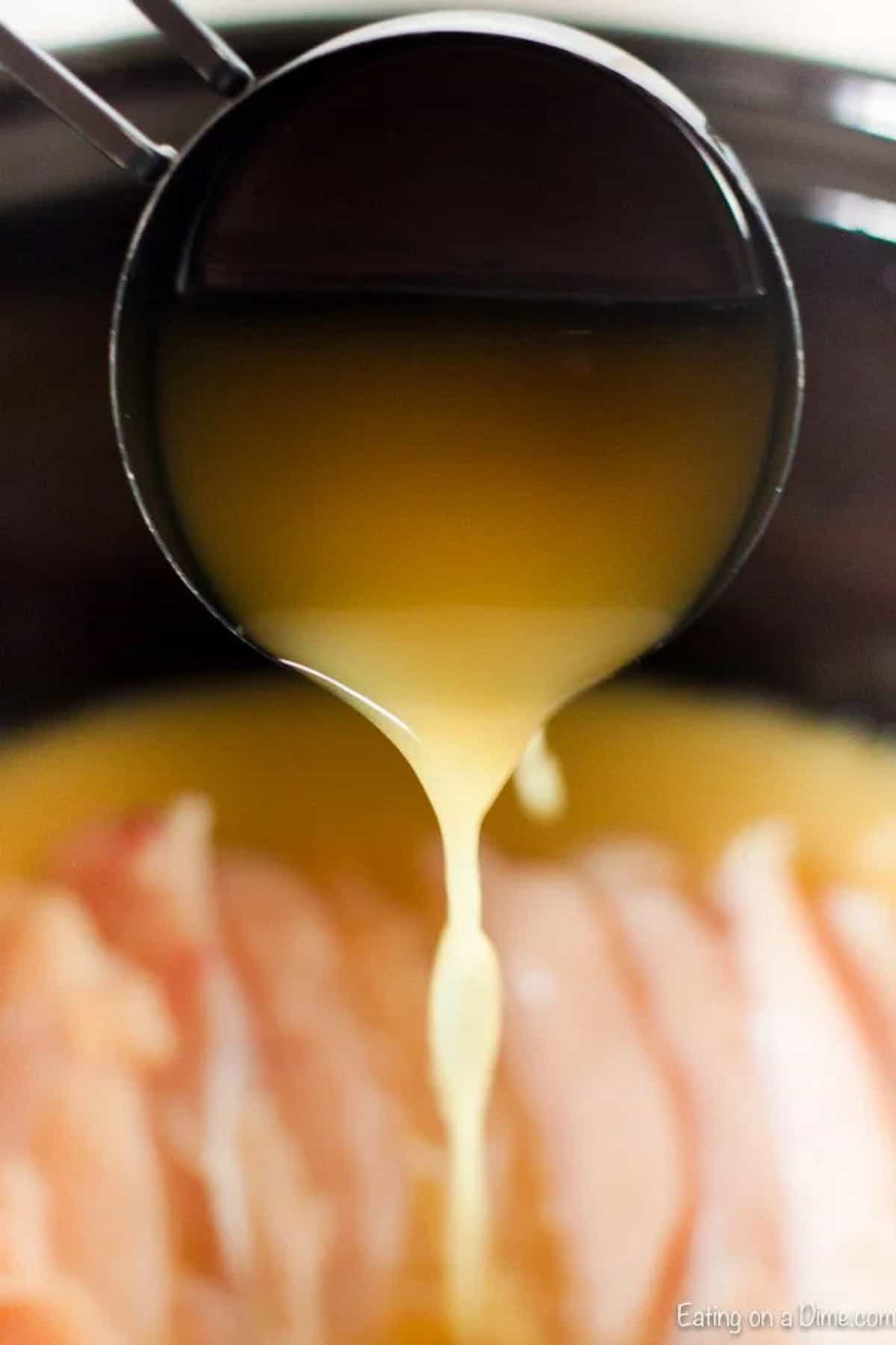 Chicken broth being poured into the slow cooker