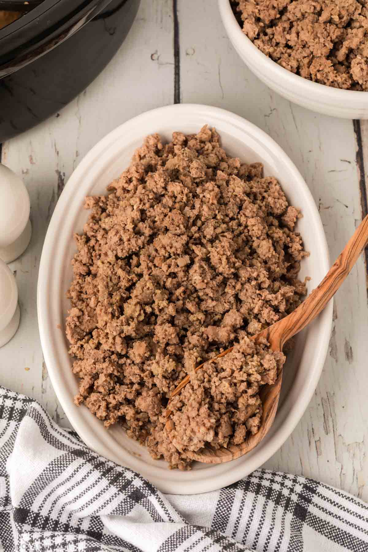 Ground Beef in a white bowl with a wooden spoon