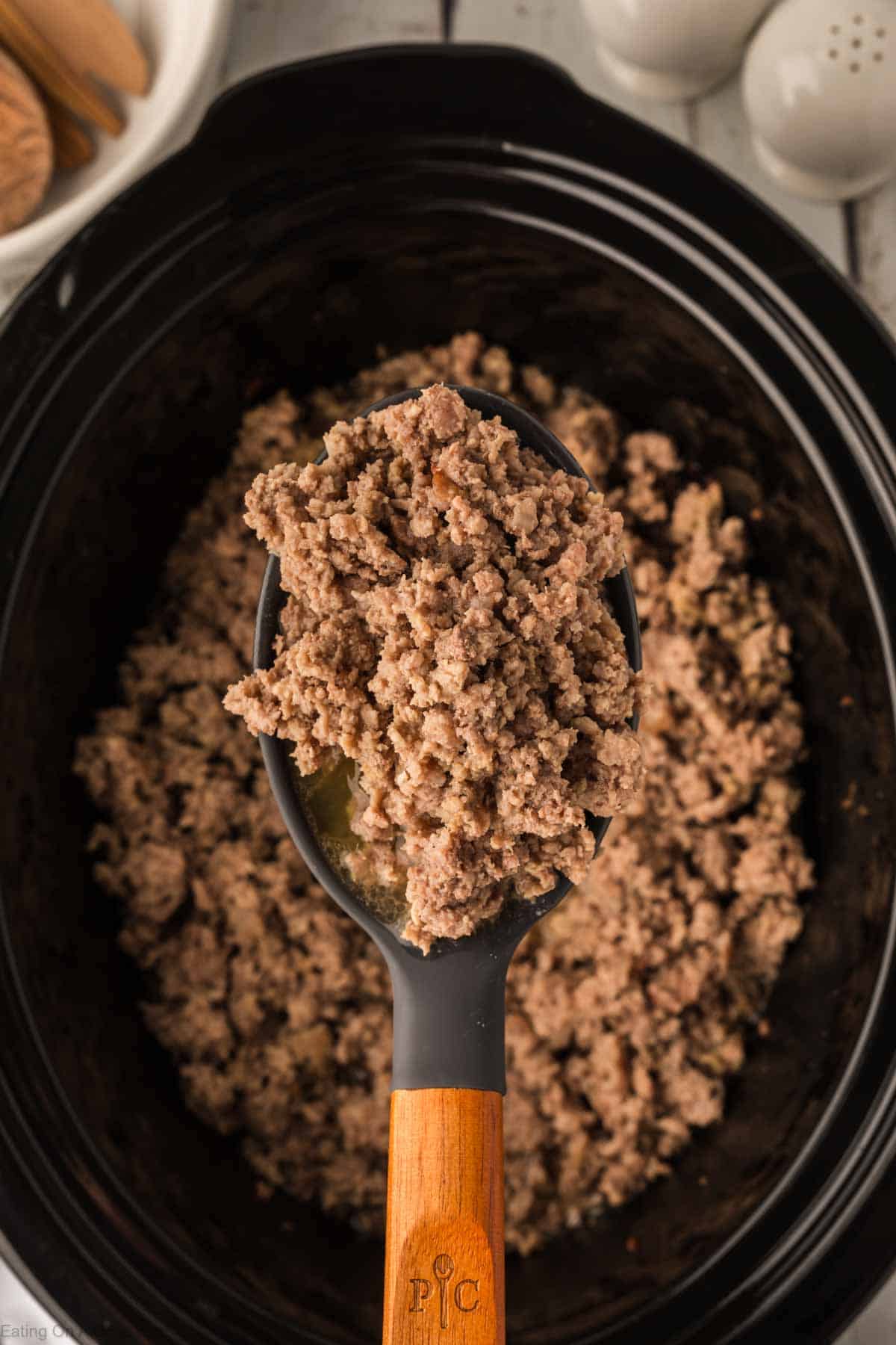 Ground beef in the slow cooker with a serving on a wooden spoon