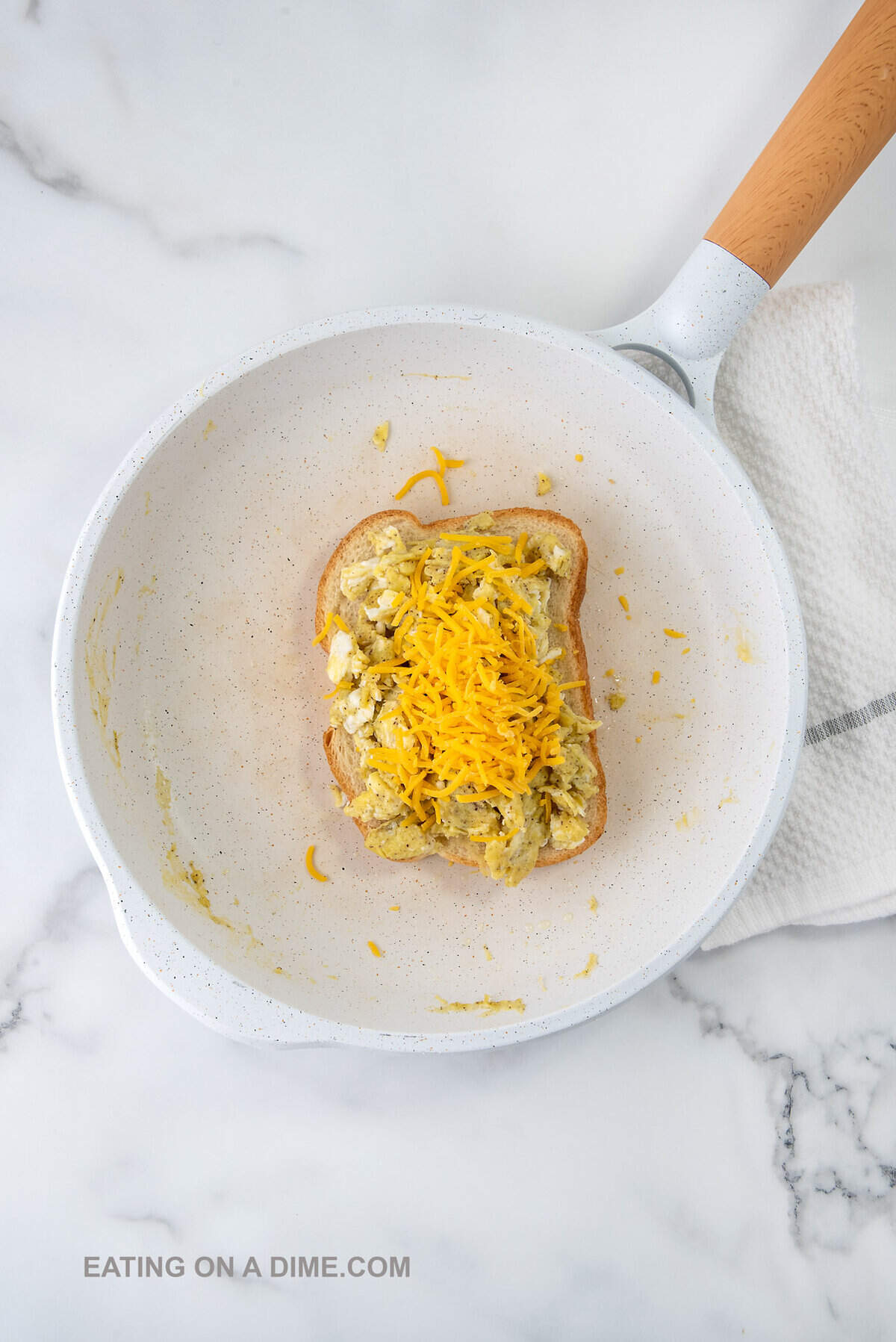 Topping the bread with scrambled eggs and shredded cheese