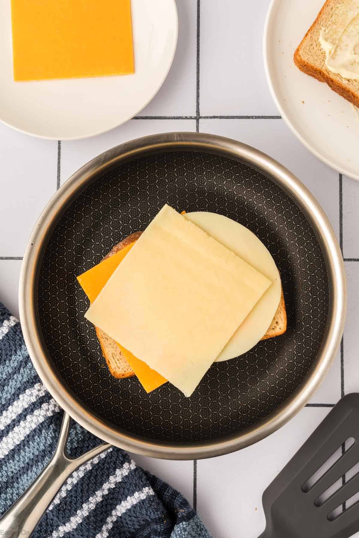 Topping the slice of bread with the three slices of cheeses