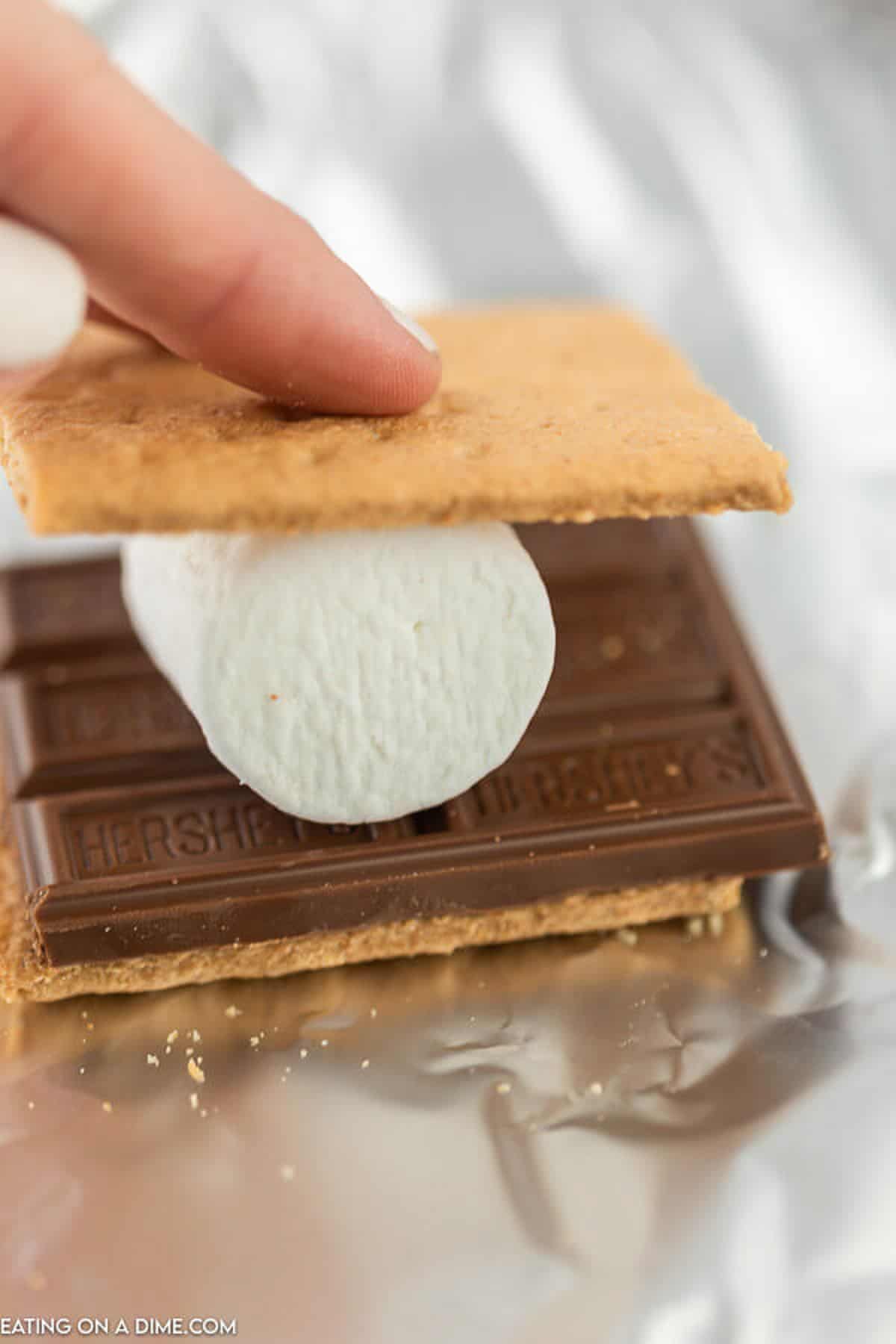 An unbaked assembled s'more on a piece of foil.  