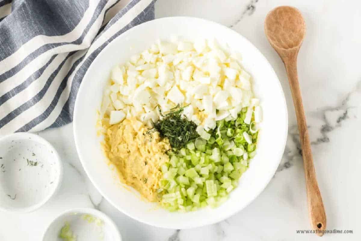 Combining the ingredients for egg salad mixture in a bowl.