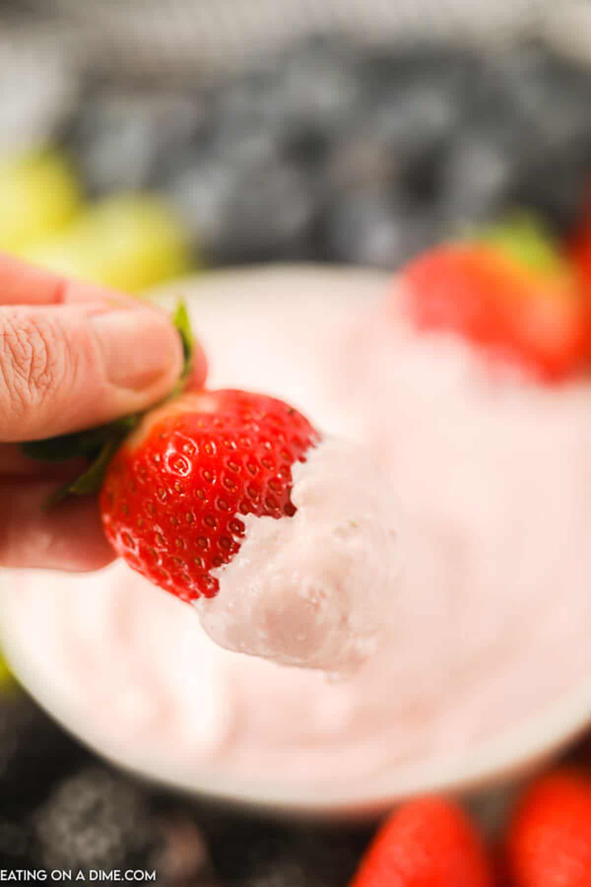 A strawberry being dipped into strawberry fruit dip