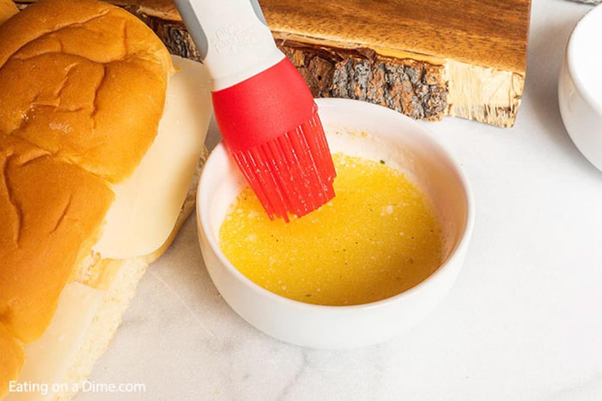 A bowl of melted butter and garlic salt with a brush