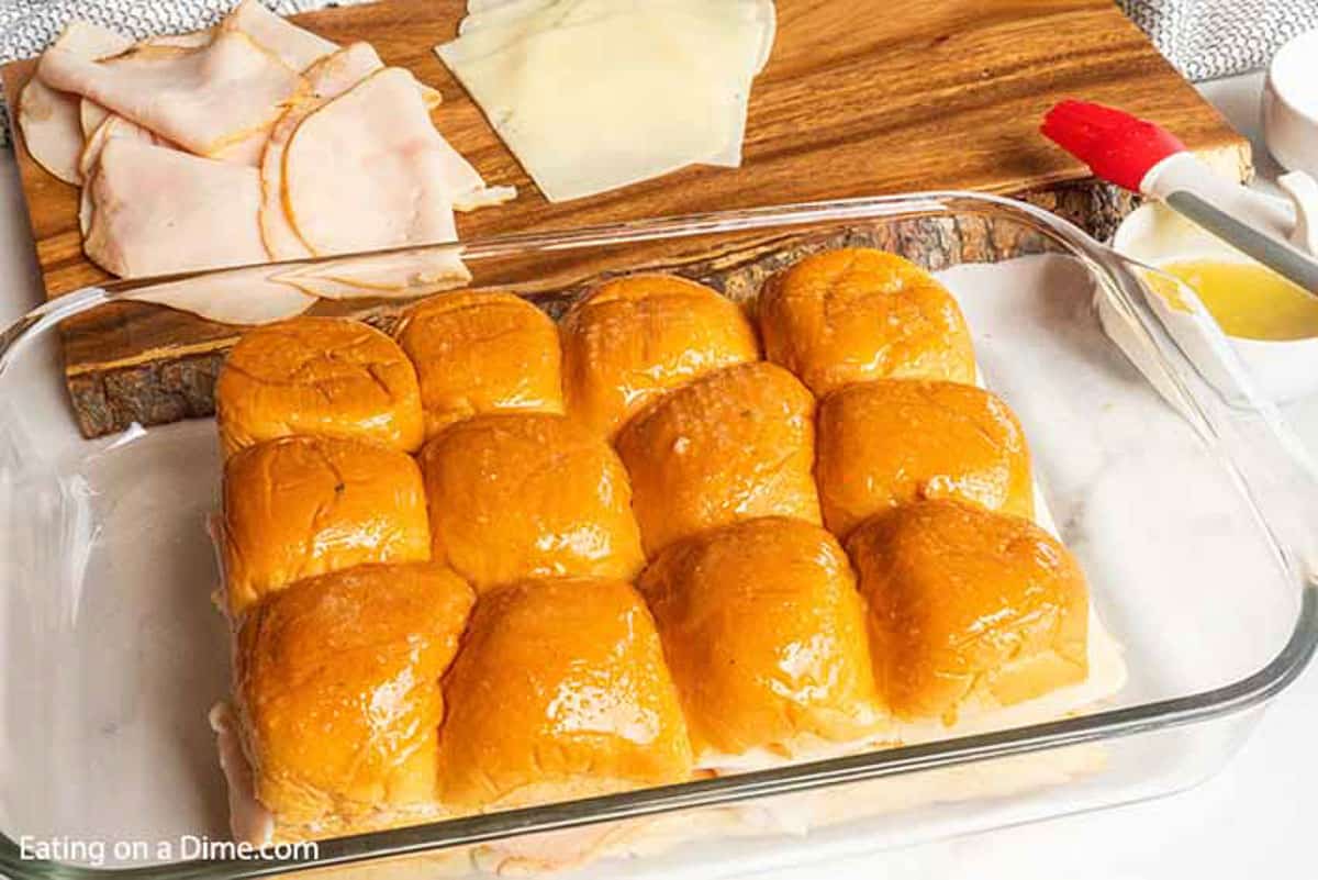 The prepared Hawaiian roll sliders placed in a baking pan ready to be baked. 