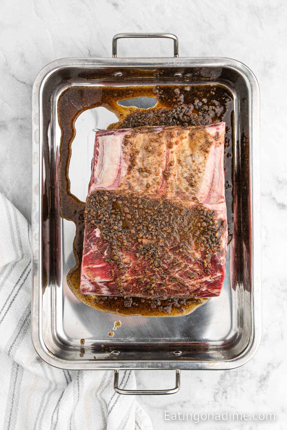 Spreading the marinade over the prime rib in a roasting pan