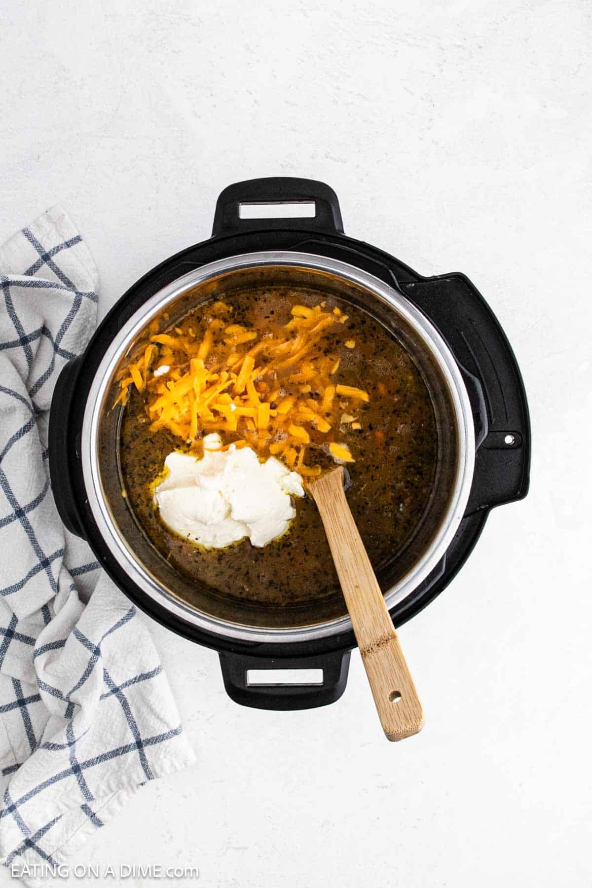 Cream cheese and shredded cheese added to the soup mixture in the instant pot.