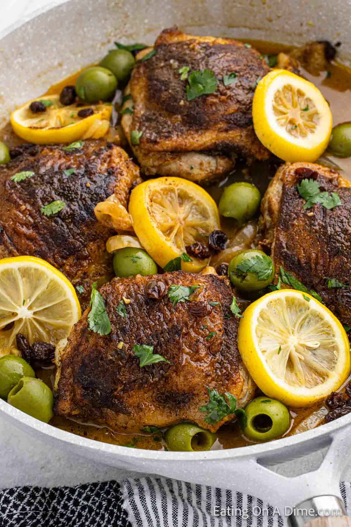 Moroccan Chicken in a skillet with slice lemons and olives