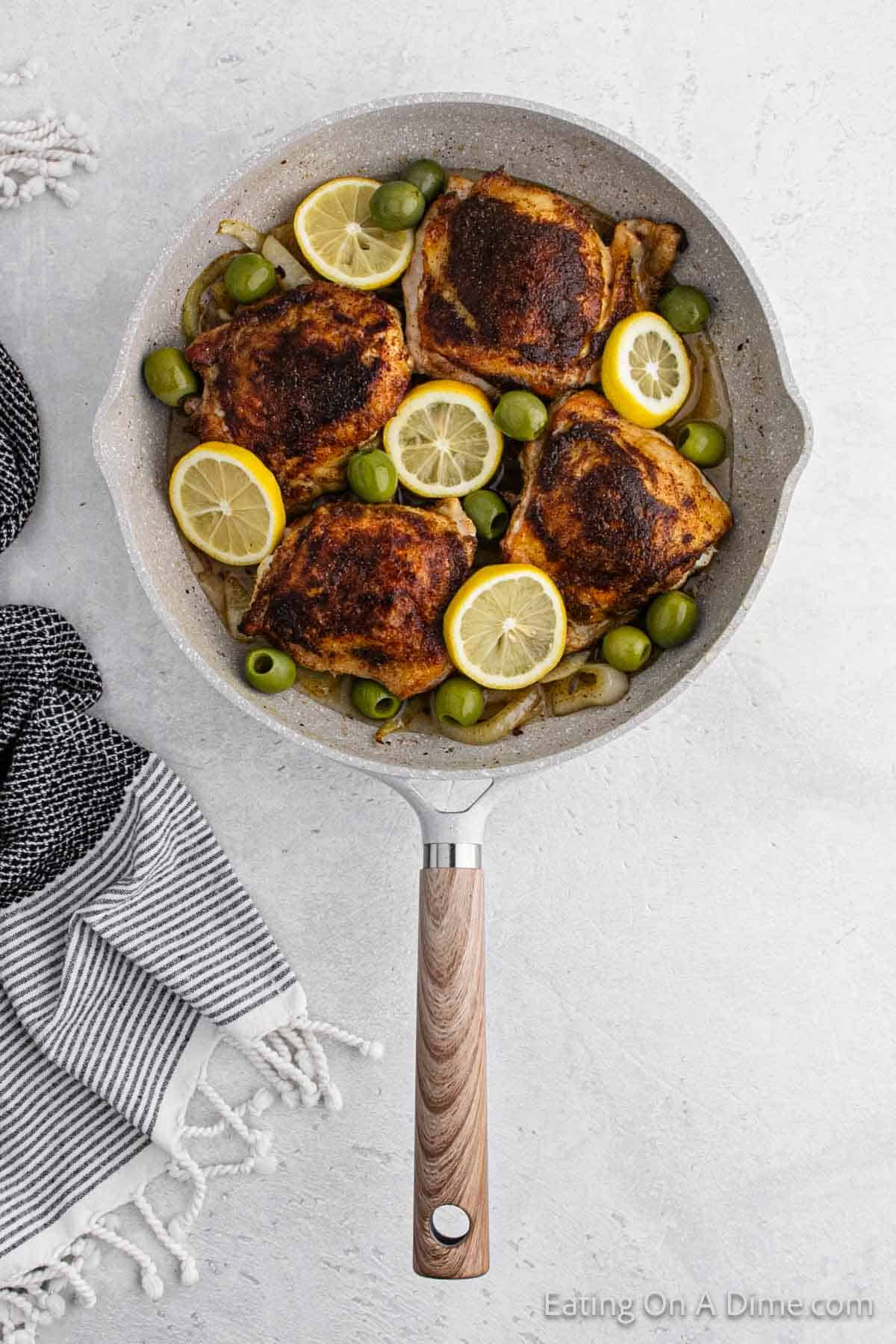 Cooked Moroccan Chicken in a skillet with lemon and olives