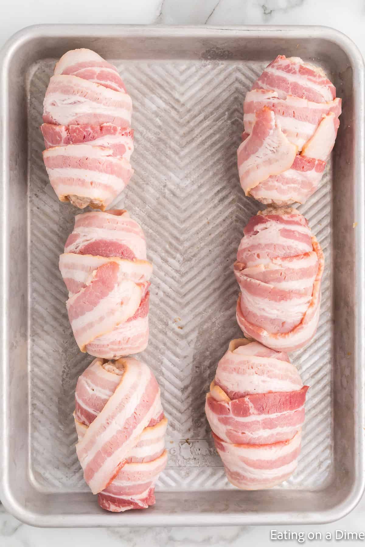 Bacon wrapped armadillo eggs on a baking sheet