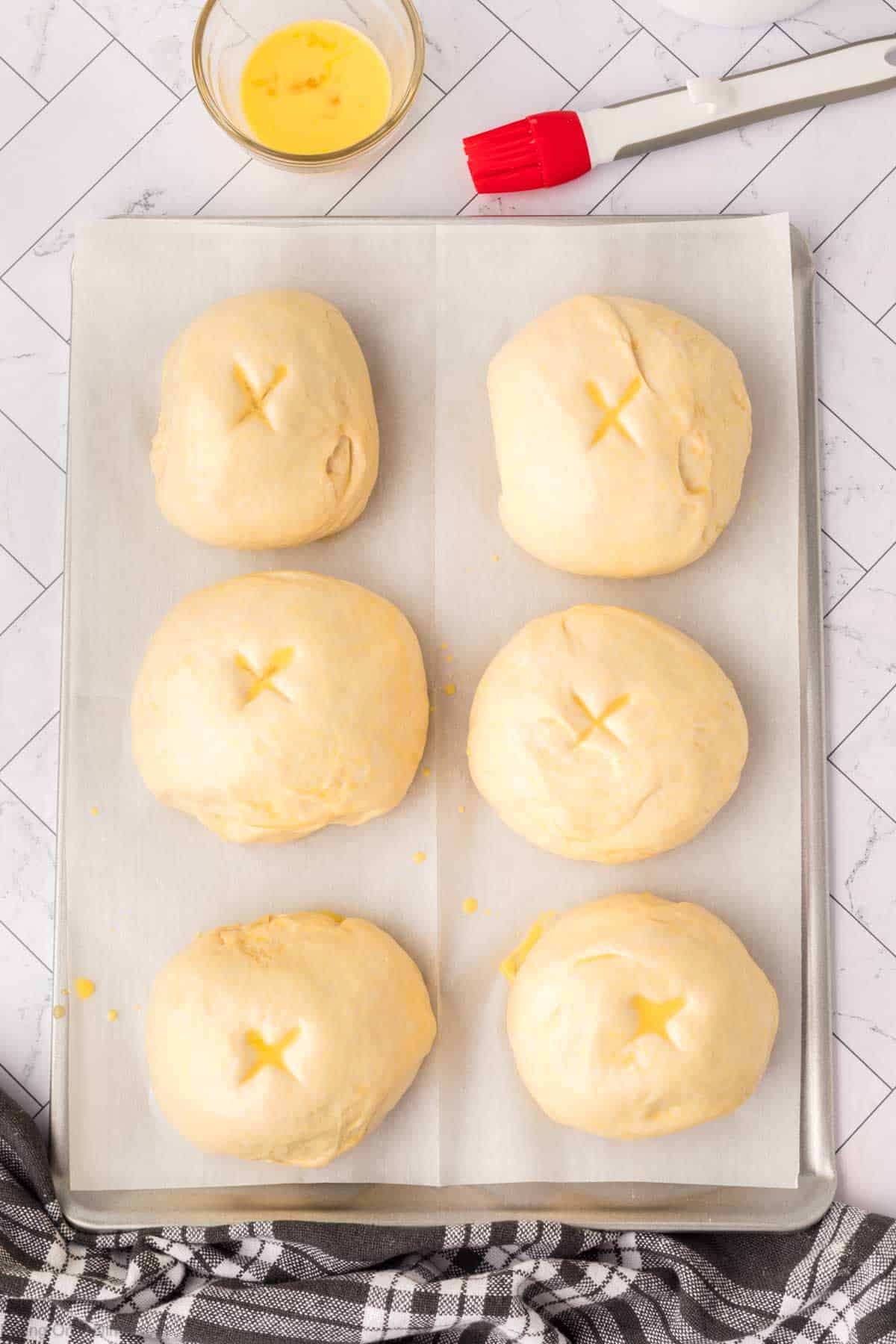 Placing dough balls on a baking sheet and topping with egg mixture