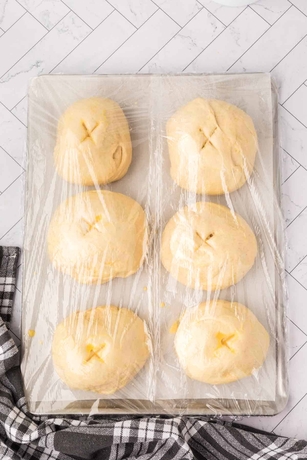 Covered dough balls on a baking sheet
