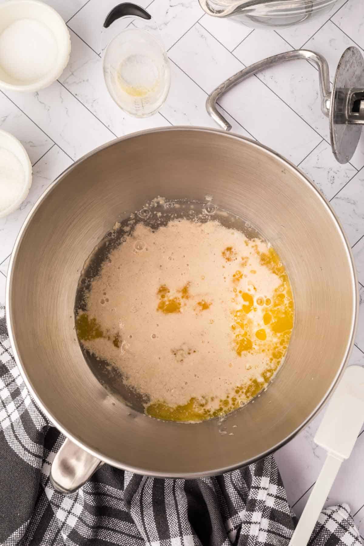 Mixing yeast, water and sugar in a bowl then adding in the melted butter