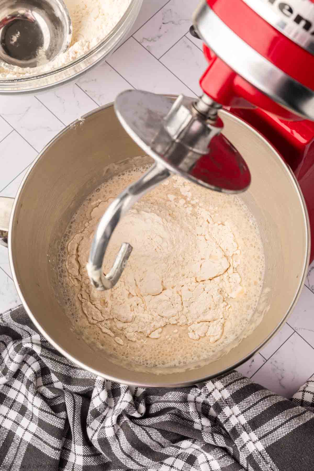 Adding in the dry ingredients to the yeast mixture with a stand mixer hook