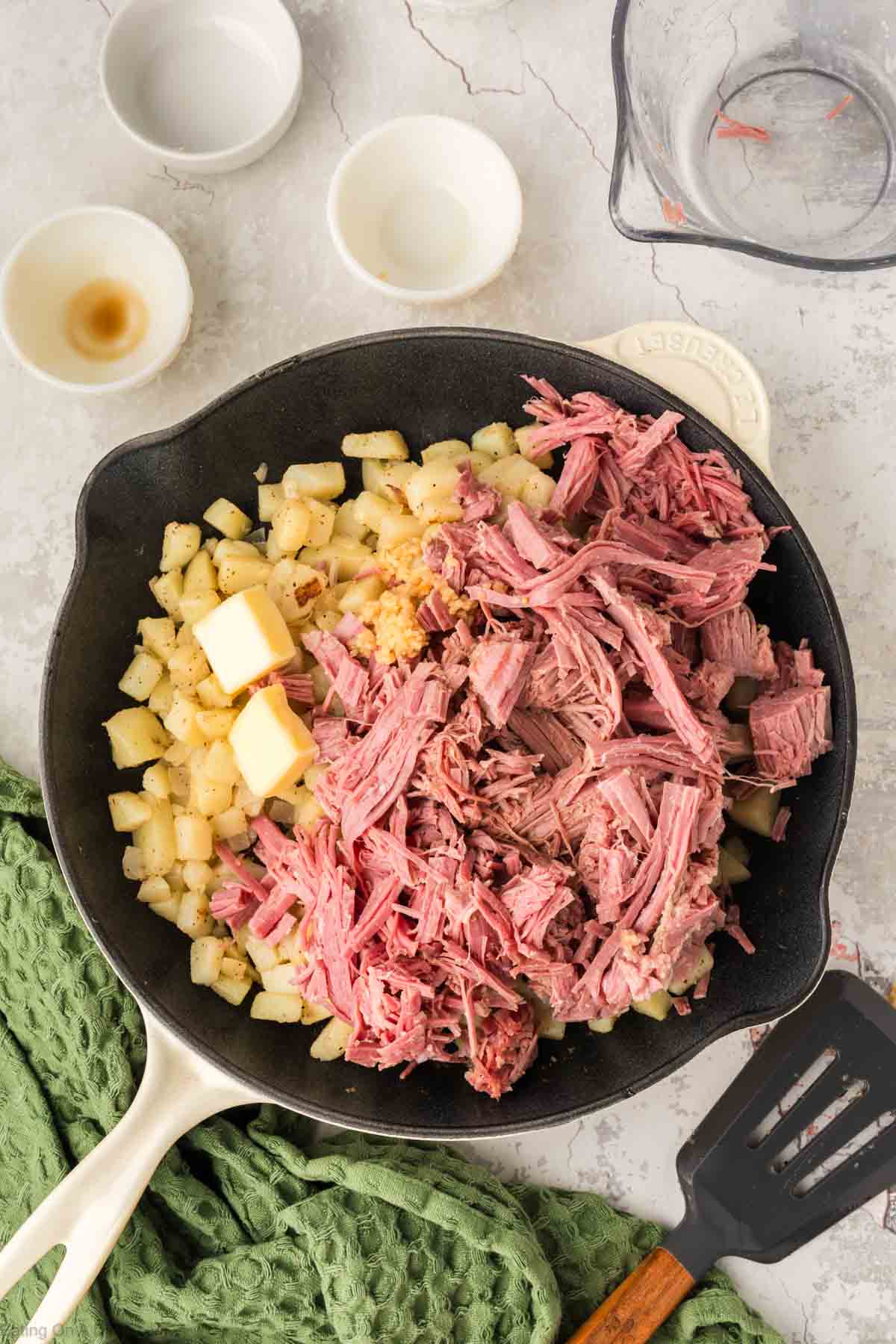 Adding in the corned beef and butter to the skillet with the vegetables