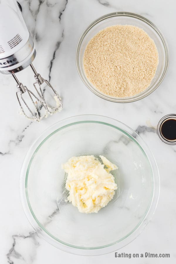 Beating the butter and sugar together in a bowl with a bowl of almond flour on the side