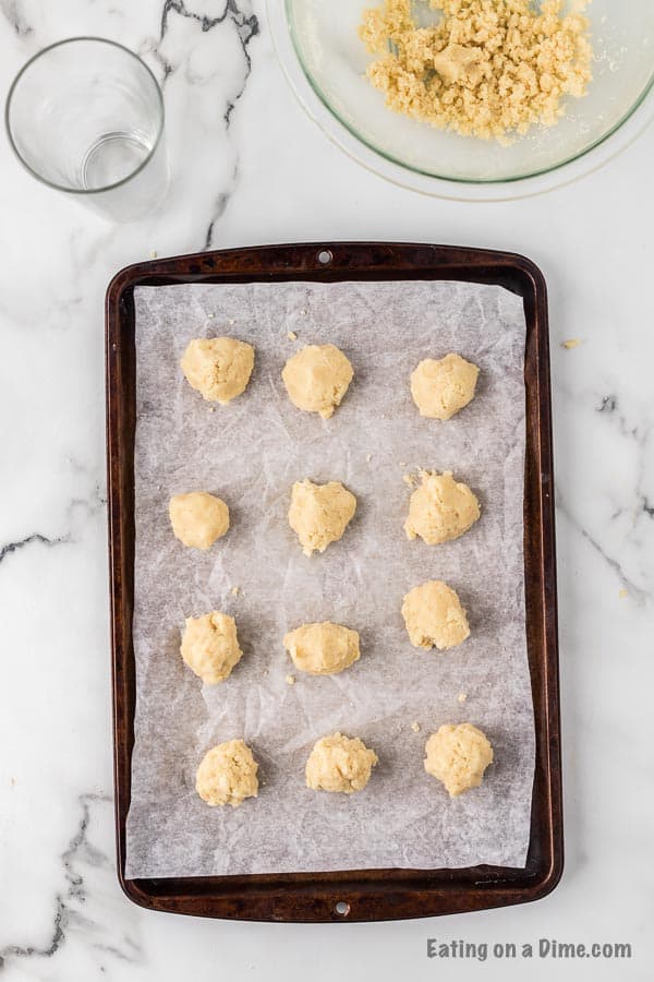 Cookie dough in balls on a parchment lined baking sheet