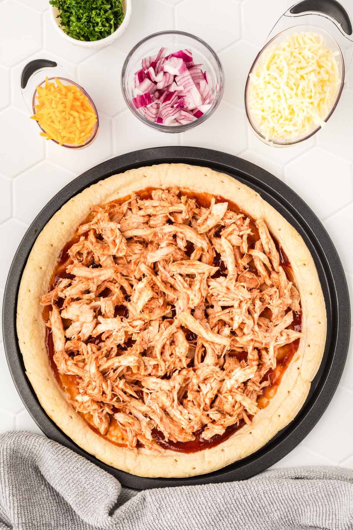 Topping the Pizza Crust with Shredded BBQ Chicken