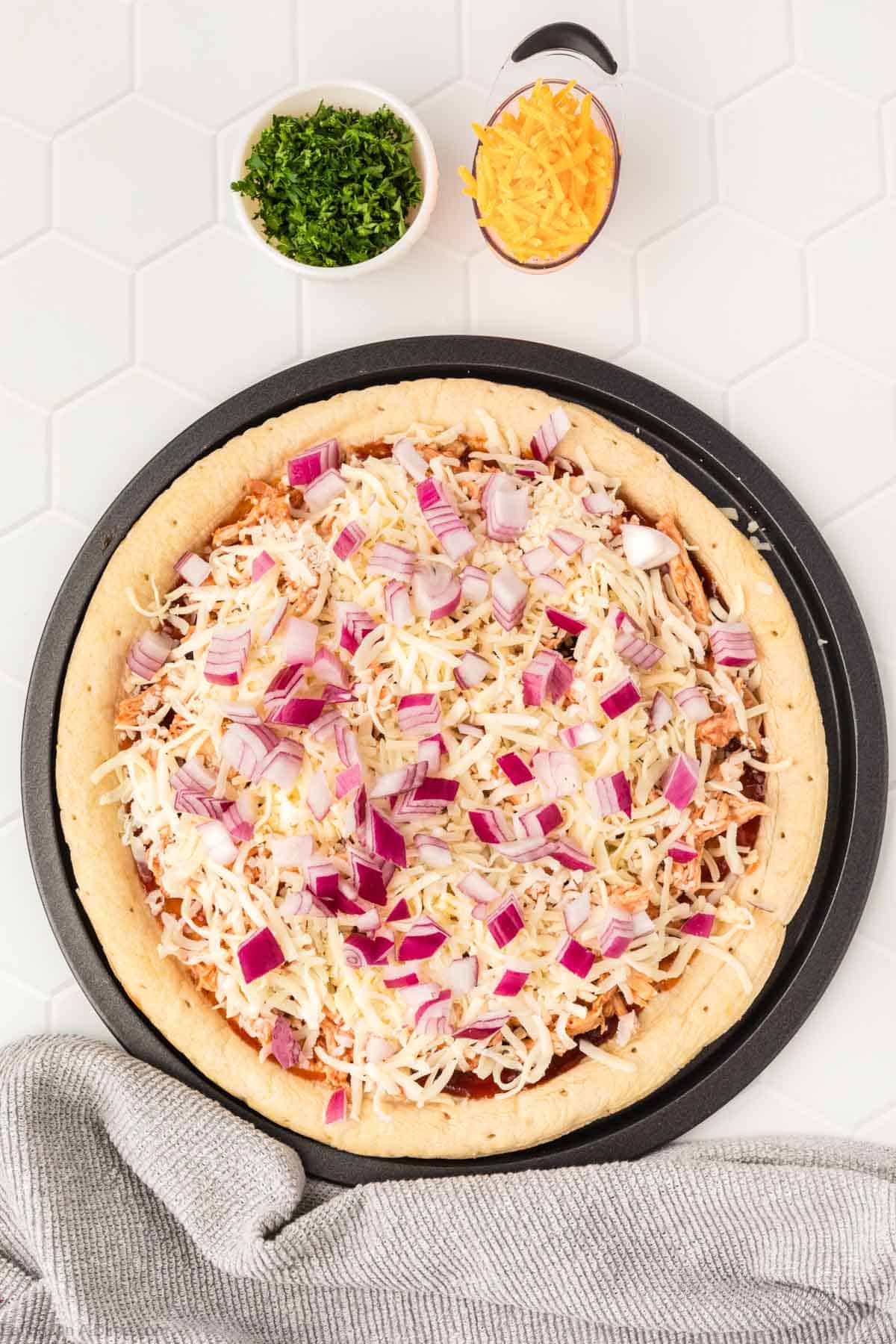 Adding Shredded Cheese and Red Onion to the pizza