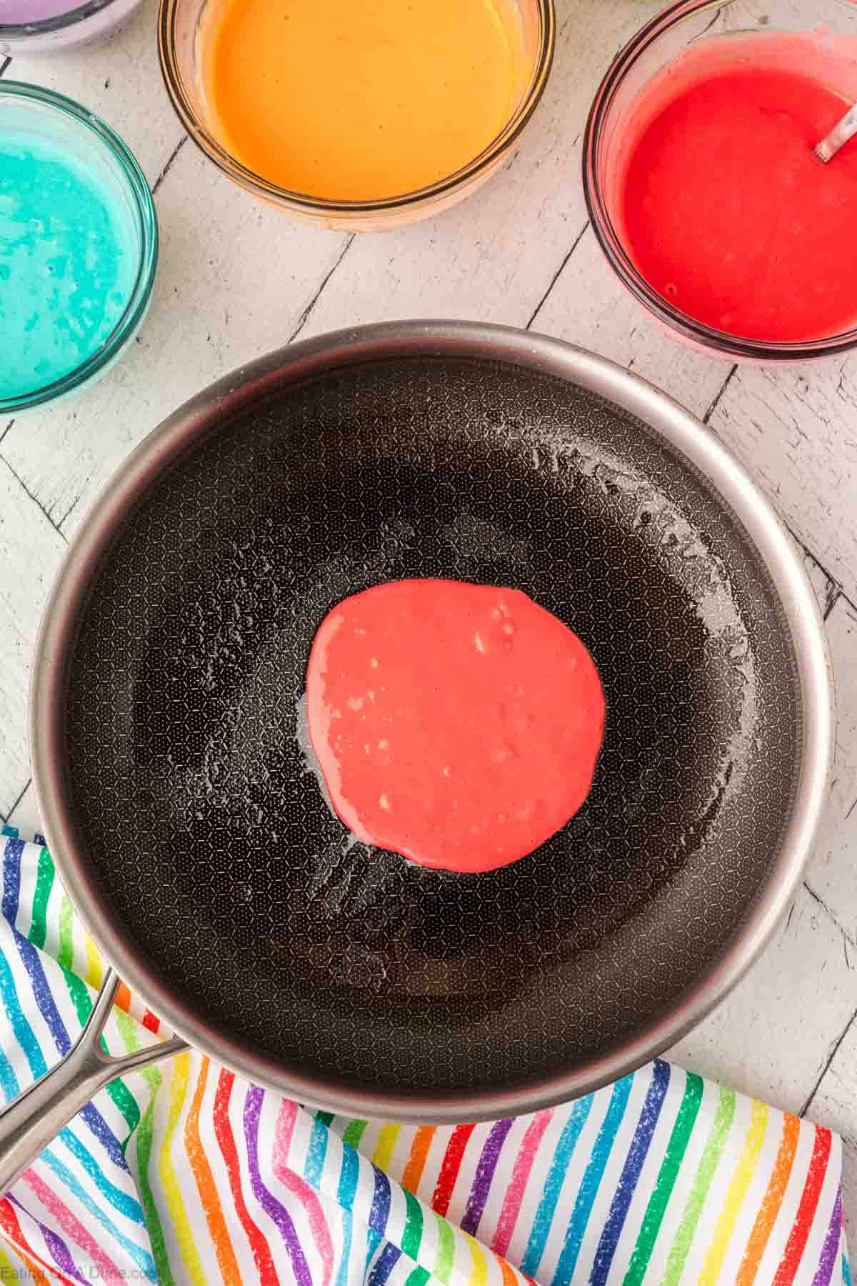 pouring red pancake batter into hot skillet