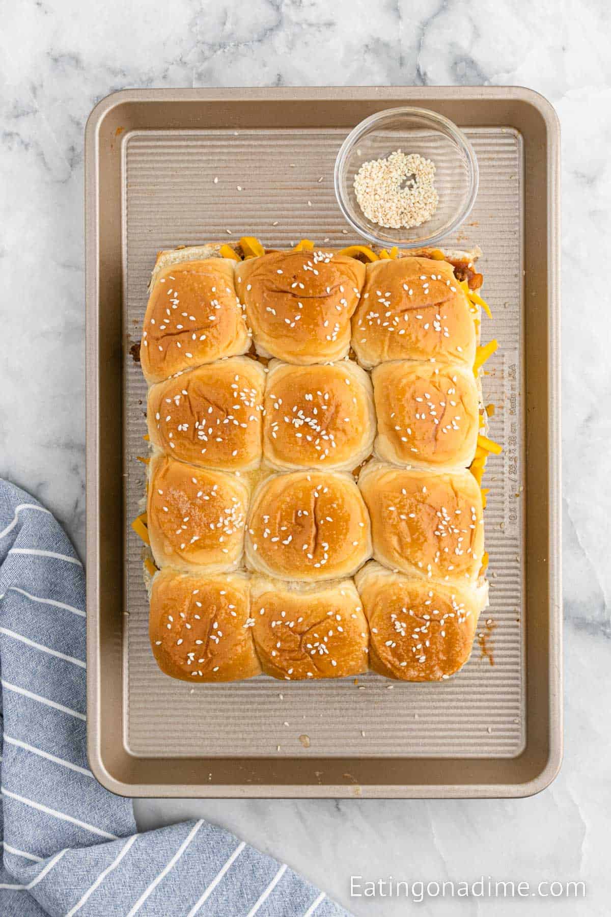 Topping the sliders with sesame seeds