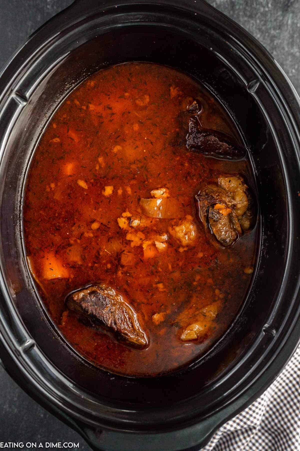 pouring the slurry in the crock pot with the cooked short ribs