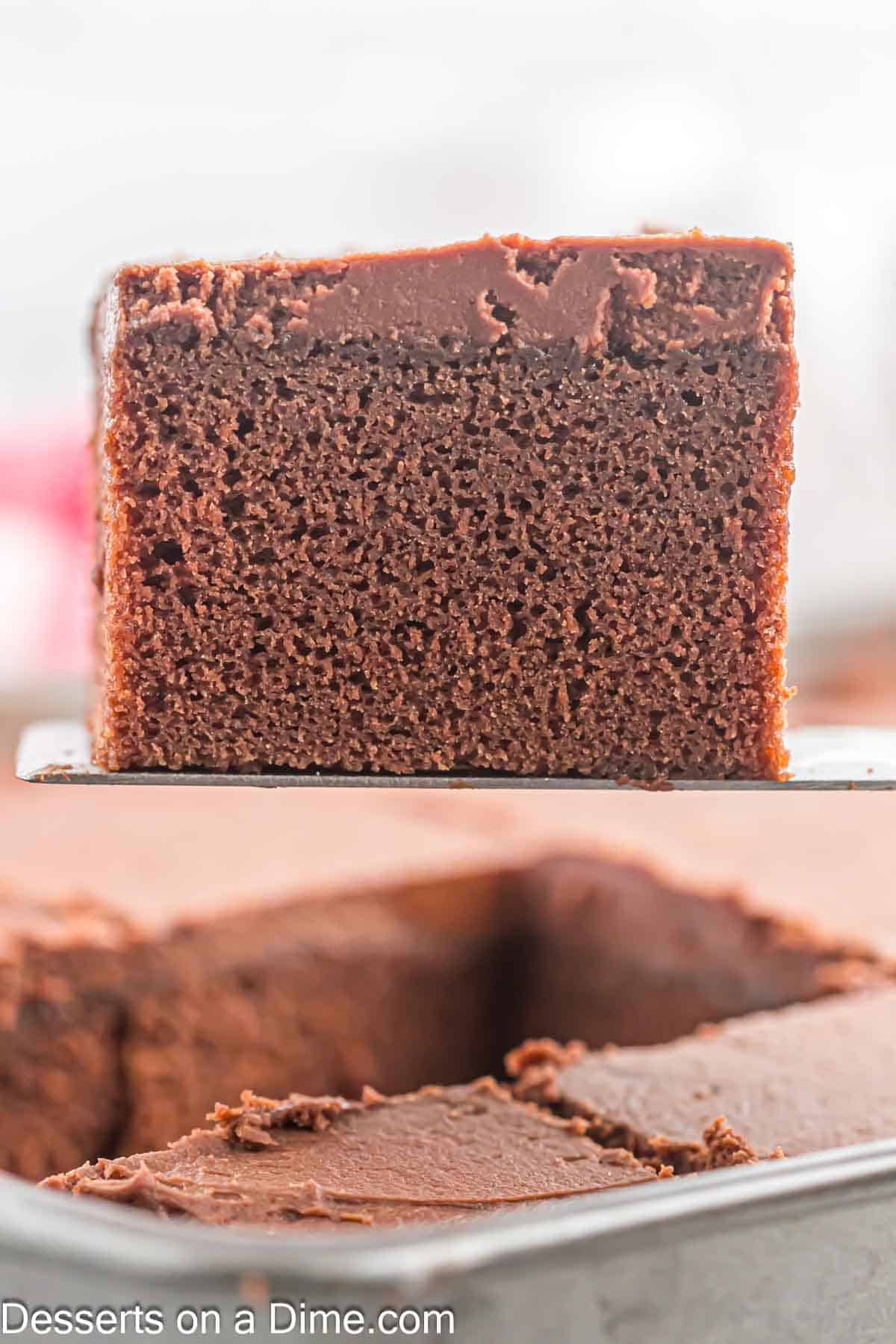 Chocolate cake in a baking dish with a slice of cake on a spatula