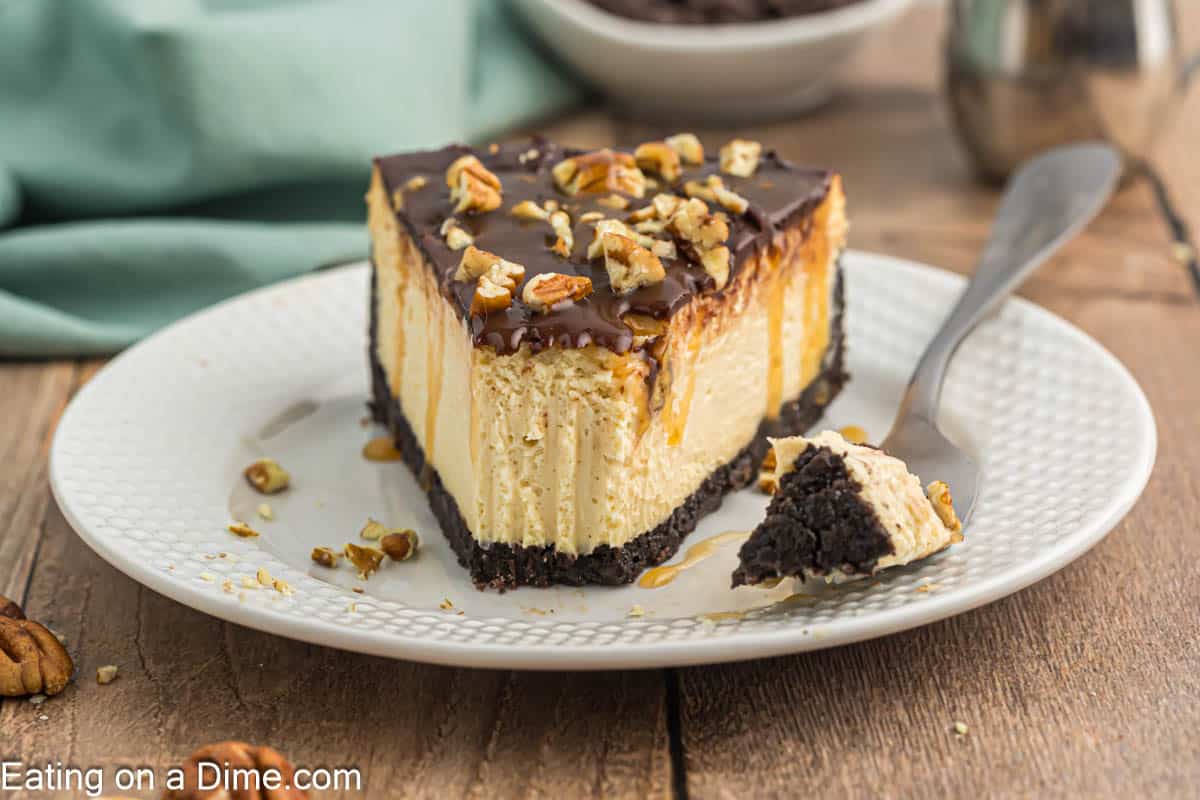 Slice of Turtle Cheesecake topped with chopped pecans on a plate.