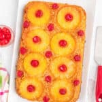 A rectangular Pineapple Upside Down Cake topped with pineapple rings and maraschino cherries.
