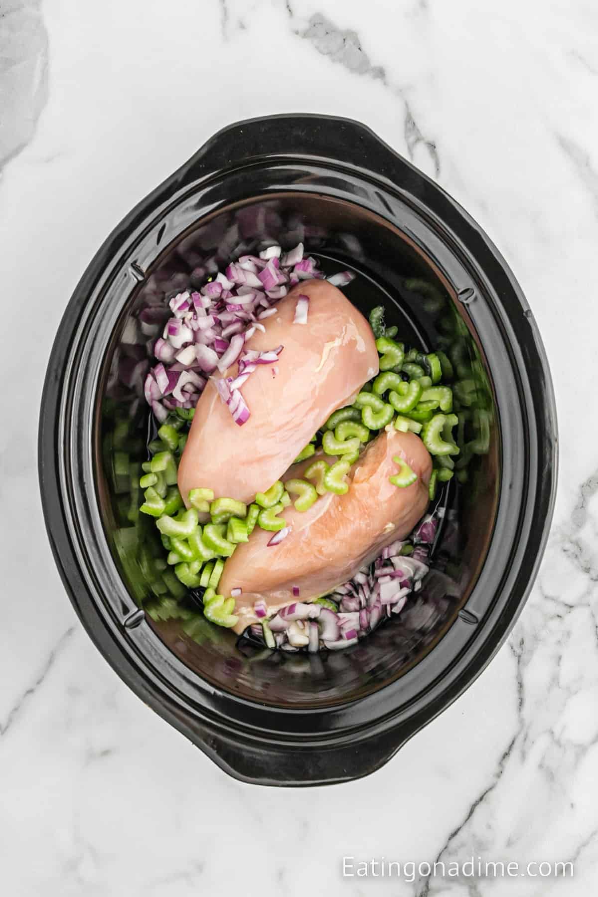 Chicken breast in the slow cooker with chopped red onions and celery