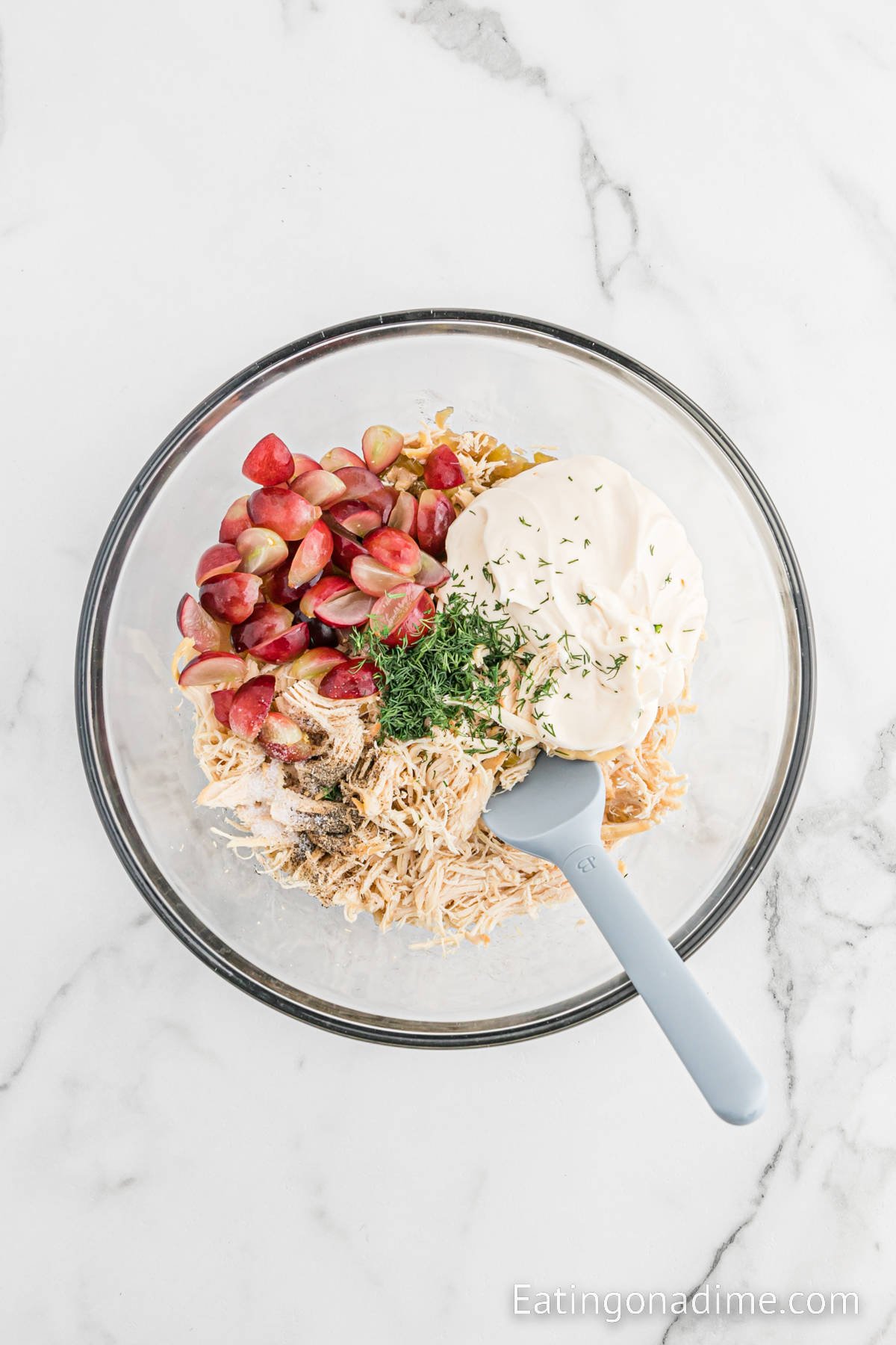 Shredded chicken, grapes, fresh seasoning and mayo in a bowl ready to combine