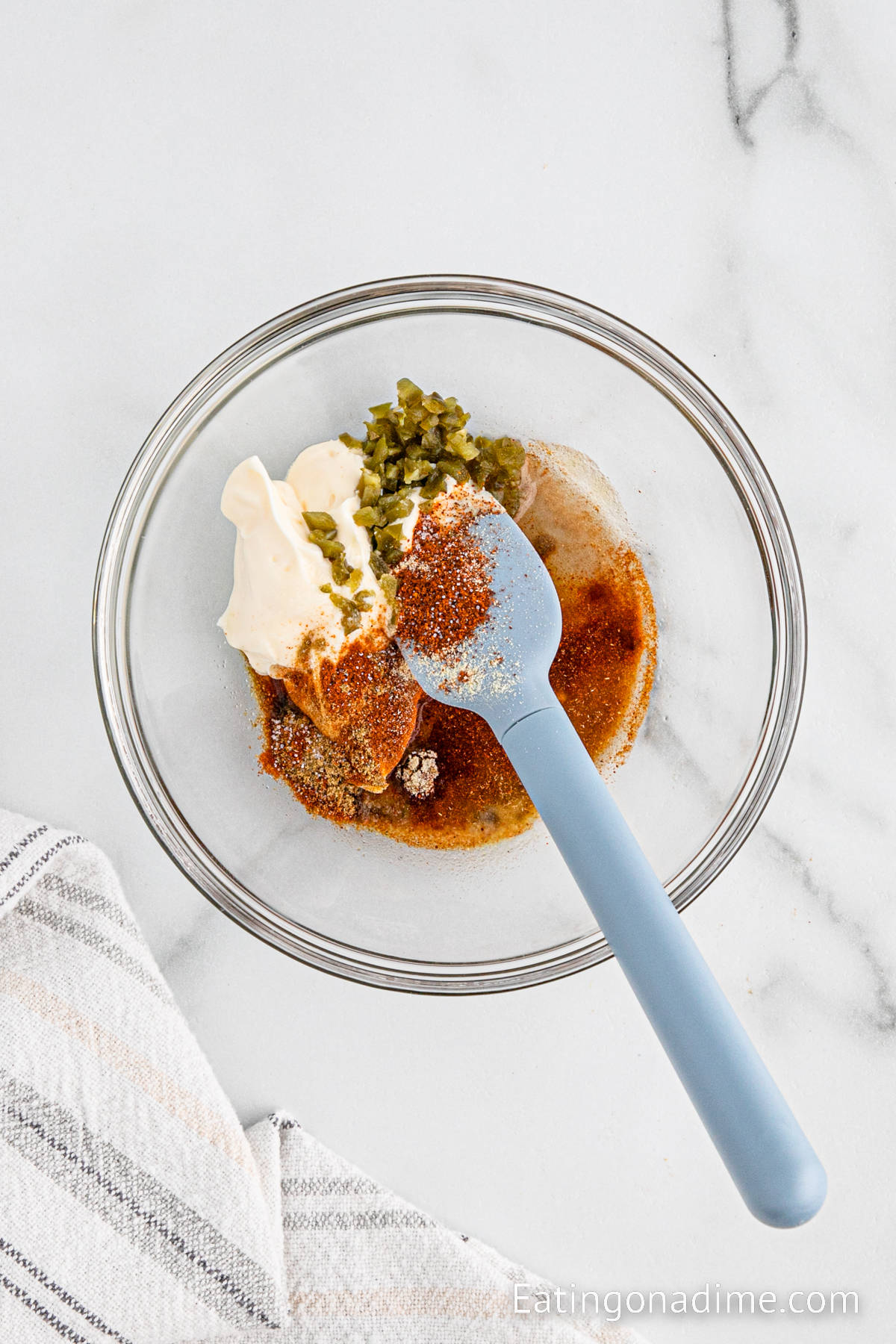 Combining the sauce ingredients together in a bowl with a blue spatula