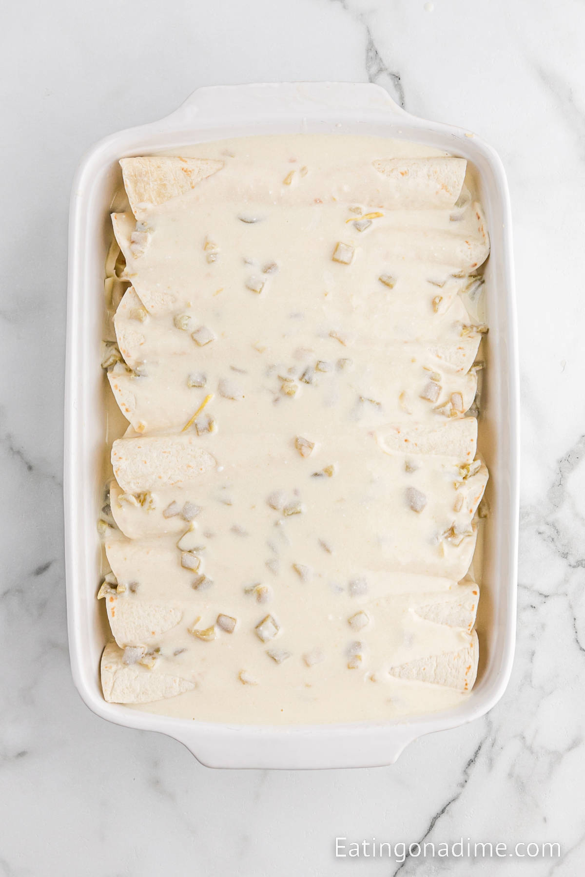 Enchiladas in a baking dish topped with a creamy sauce