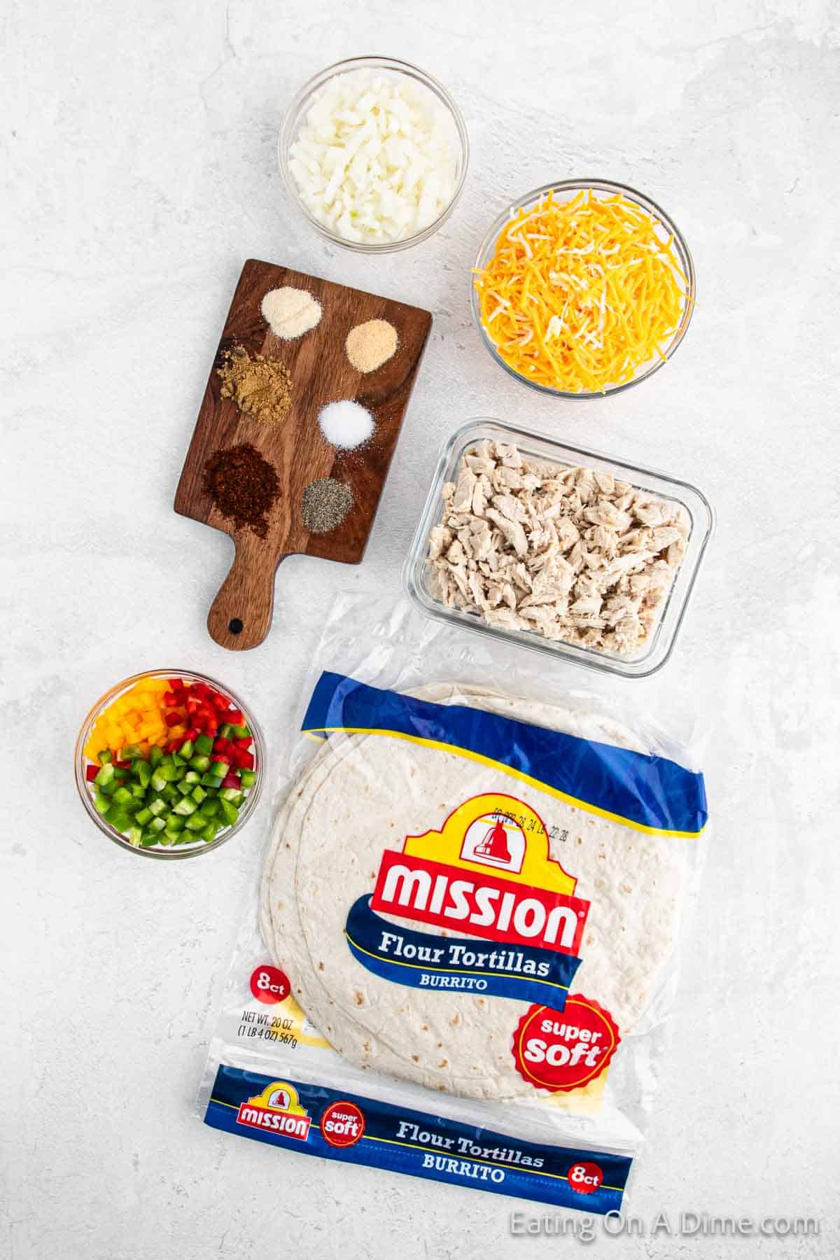 Blooming Quesadilla Ingredients - shredded cheese, seasoning, bowl of yellow, red, and green peppers, cooked shredded chicken, a package of flour tortillas