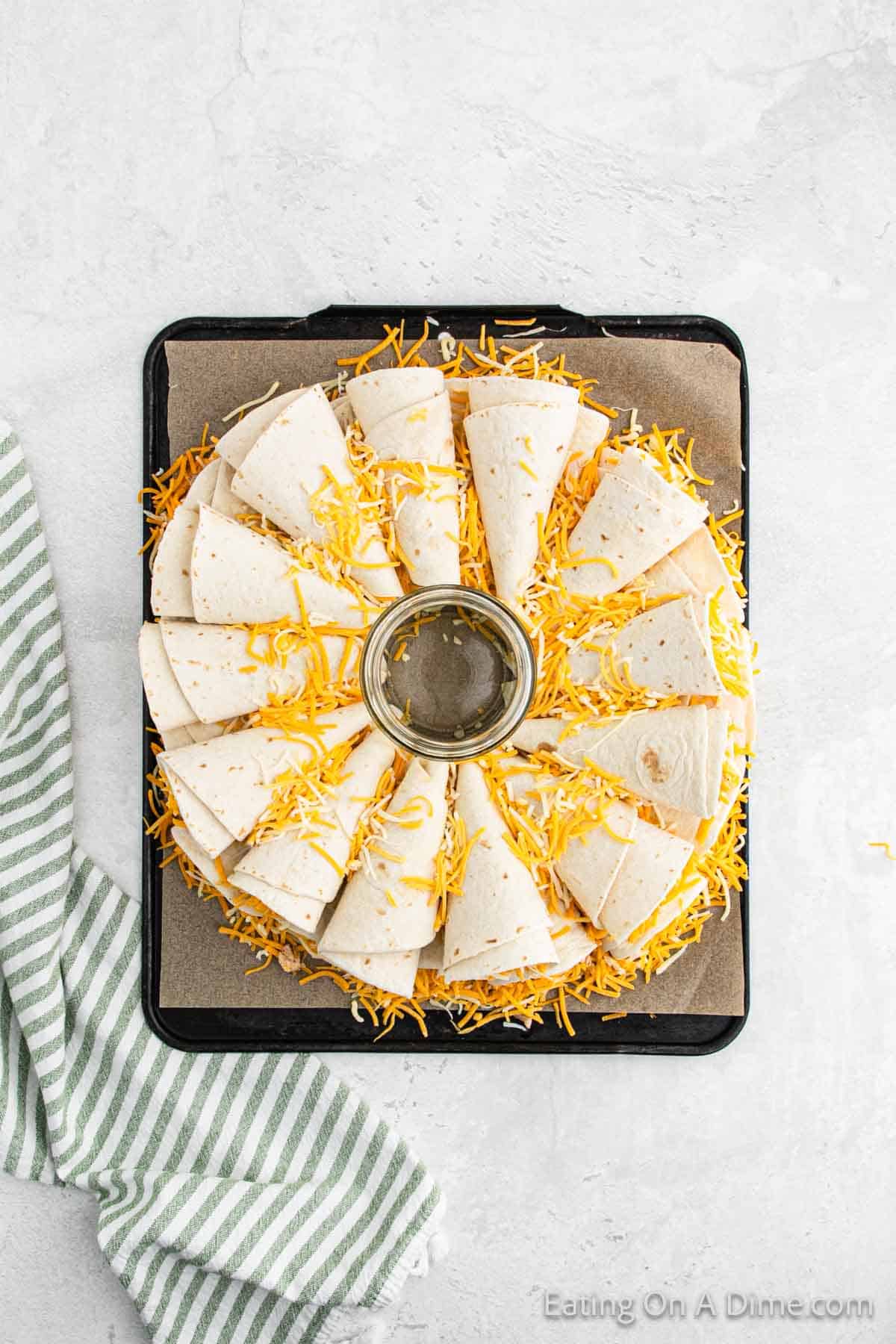 Placing the corn shape tortilla on a baking sheet topped with cheese