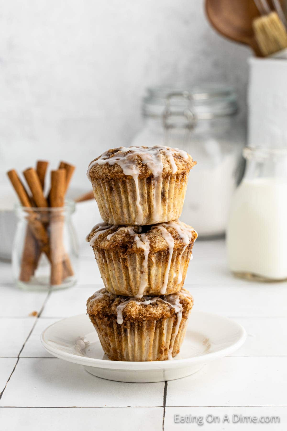 Cinnamon roll muffins stacked on a plate topped with glaze